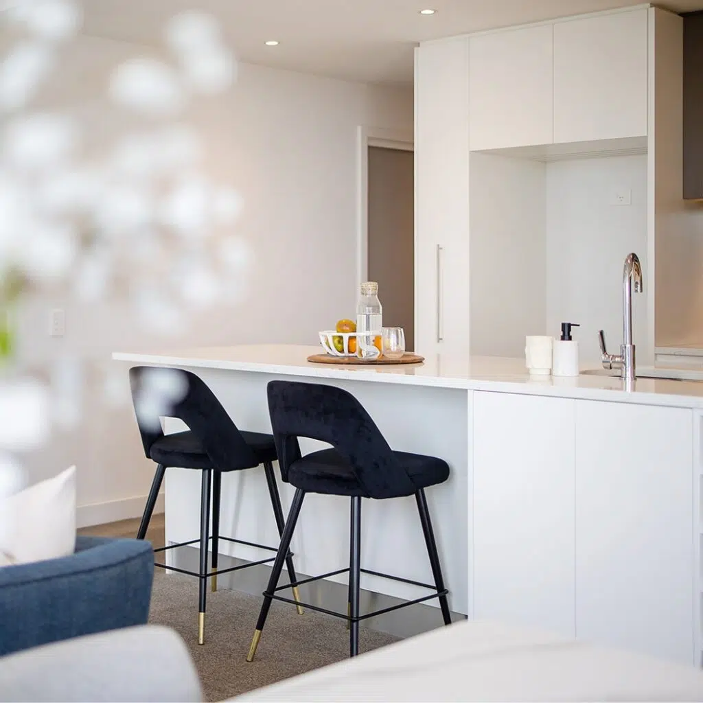 Delta Velvet Bar Stools positioned at a modern kitchen island, showcasing their plush upholstery and sleek frame, adding elegance and comfort to a contemporary kitchen space.