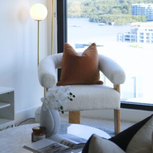 Boucle and Wood Curved Armchair - White & Natural with cushion placed in the living room