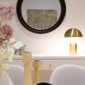 White console table styled with vases and artwork behind a sofa