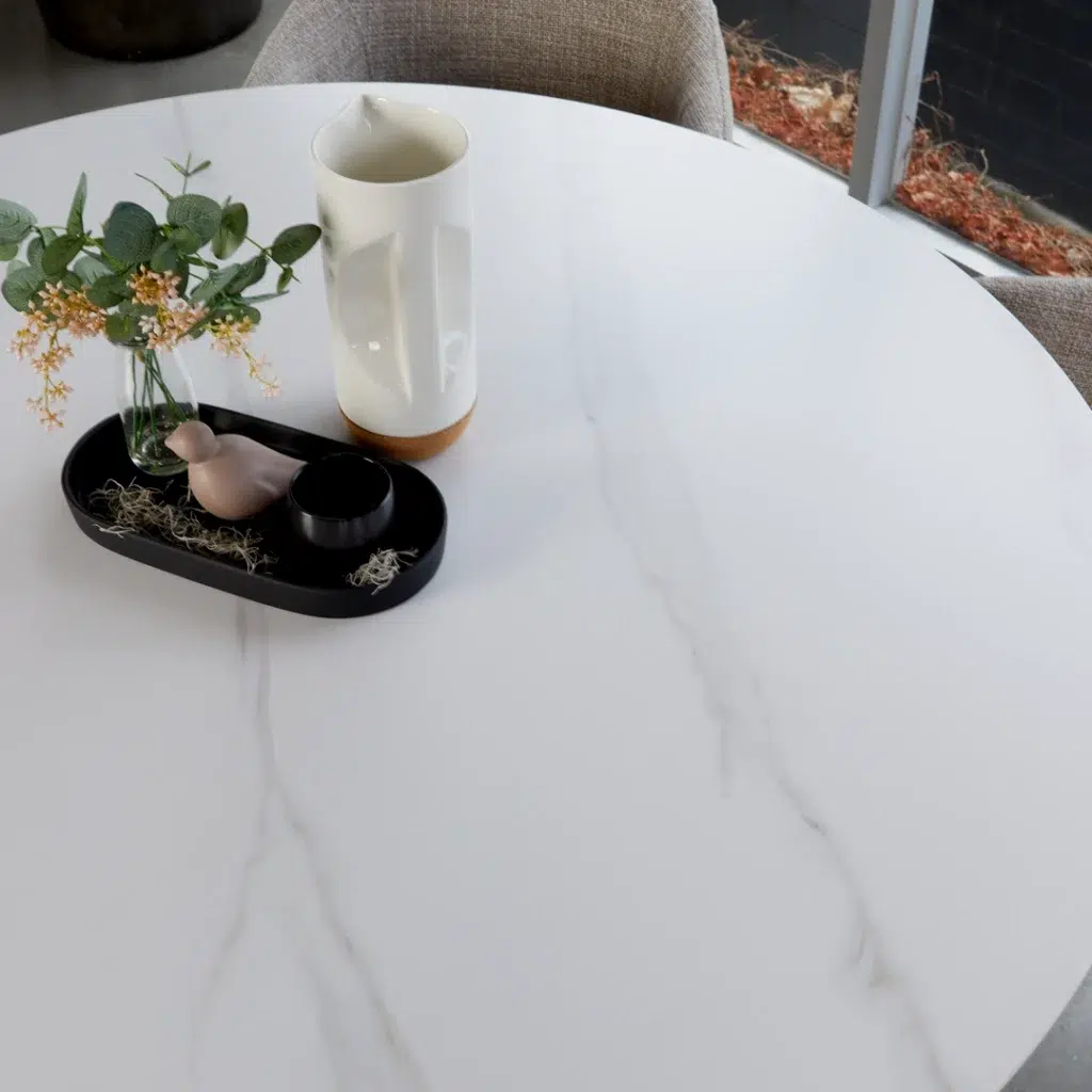 White round dining table with marble-effect top and sculpted column bases