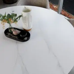 White round dining table with marble-effect top and sculpted column bases