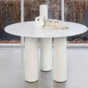 White round dining table with marble-inspired ceramic top and sculpted column legs