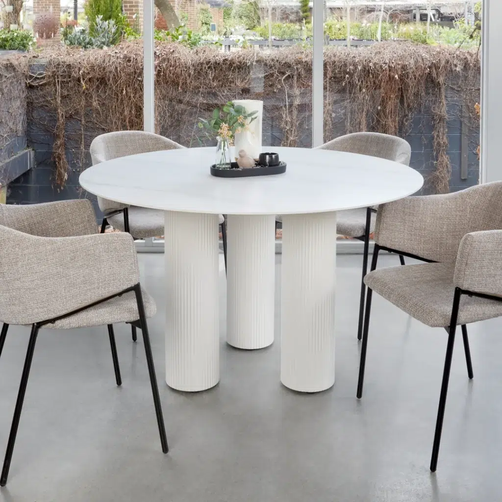 White round dining table with marble-inspired ceramic top and sculpted column bases