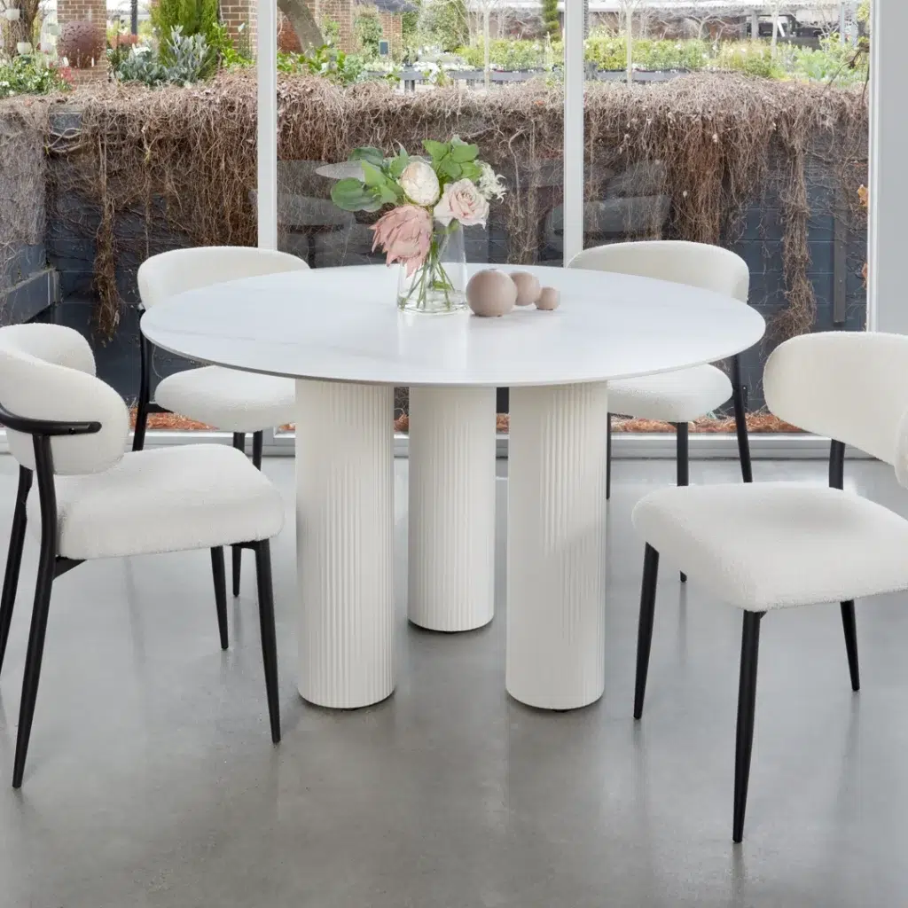 White round dining table with marble-inspired ceramic top and sculpted column bases